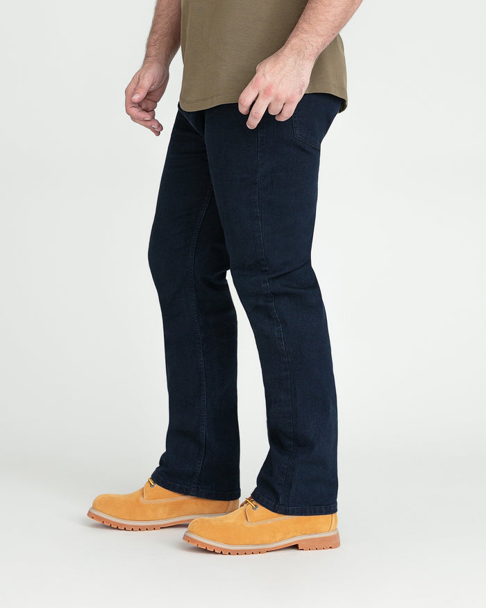 Man wearing deep blue bootcut jeans with tan shirt and tan work boots.