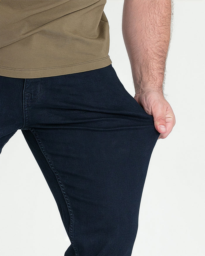 Deep blue bootcut jeans shown on model wearing tan shirt.