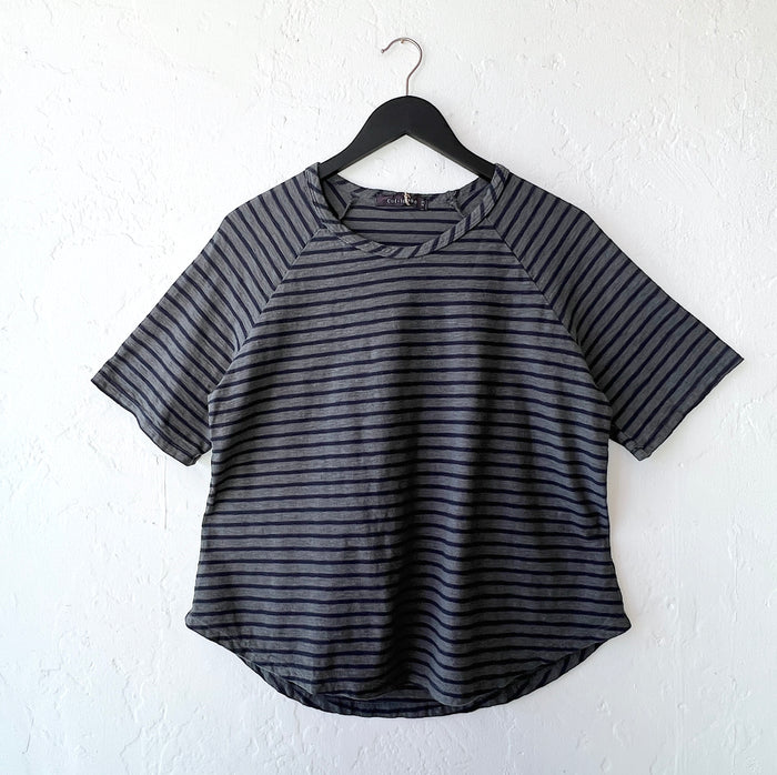 Black and gray striped shirt on a hanger against a white wall