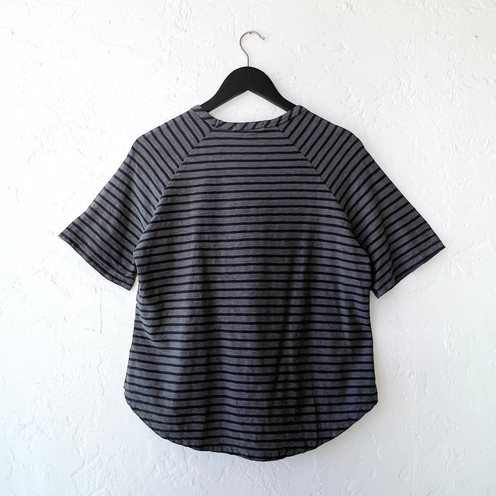 Black and gray striped shirt on a hanger against a white wall as viewed from the back