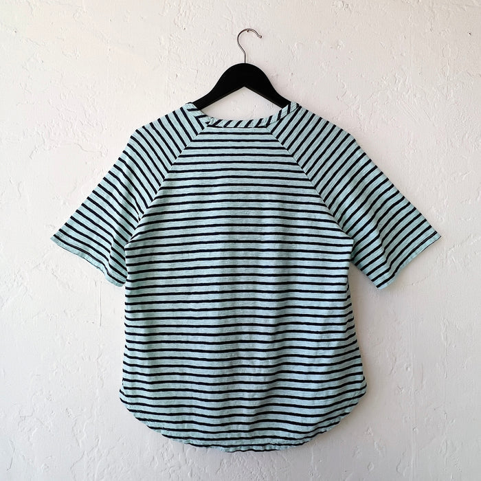 Striped shirt on a hanger against a white wall, viewed from the back