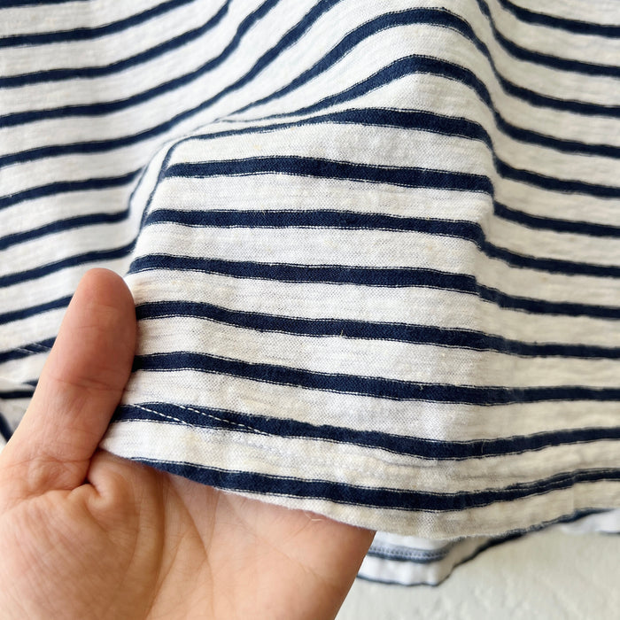 Close-up of a hand holding striped fabric with navy and white lines.