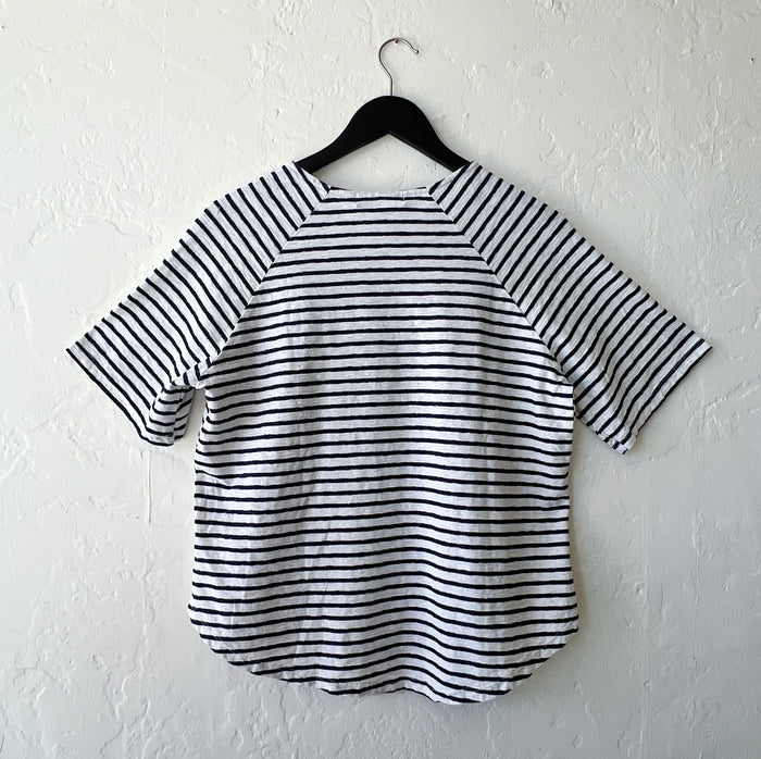 Navy and white striped shirt on a hanger against a white wall