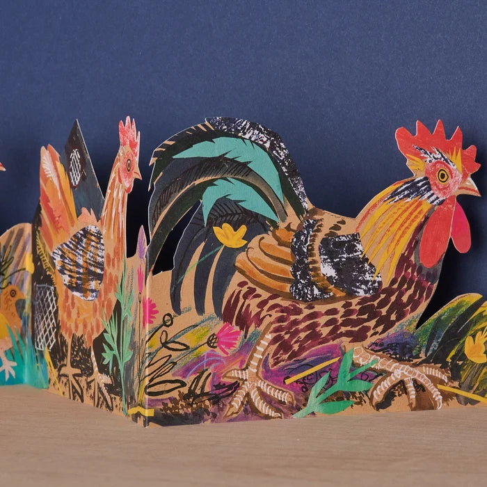 Colorful paper cutout of roosters on a dark blue background