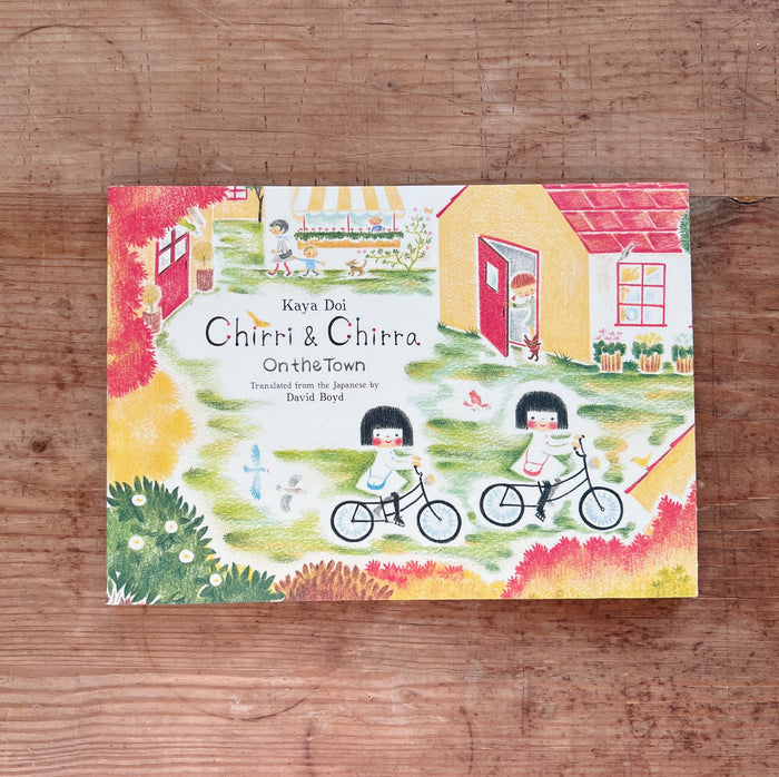 Children's book titled 'Chirri & Chitra On the Town' by Kaya Doi on a wooden surface