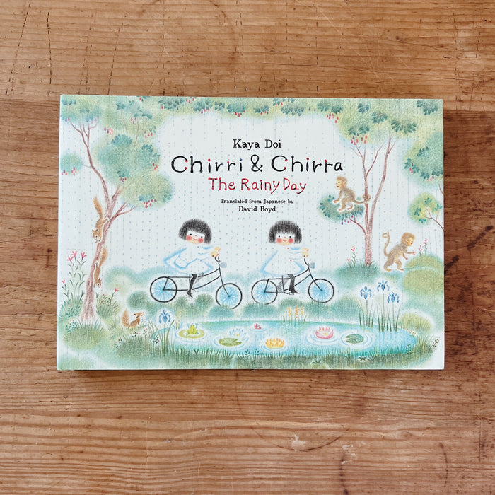 Cover of the book 'Chirri & Chirra: The Rainy Day' depicting two small figures on bicycles in a whimsical rain-filled world.