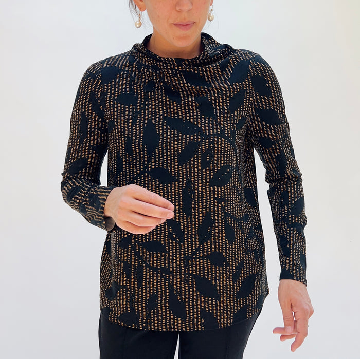 Person wearing a patterned long-sleeve top against a white background