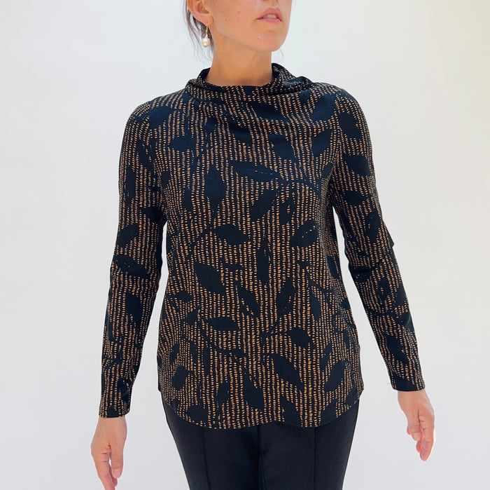 Woman wearing a long-sleeve top with a black and gold pattern on a white background