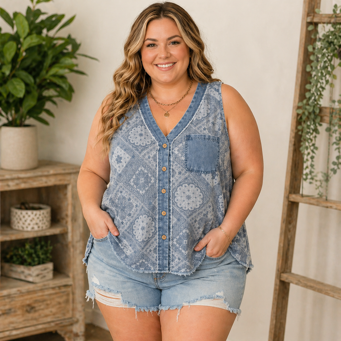 Woman wearing a blue patterned sleeveless shirt and denim shorts in a home setting.