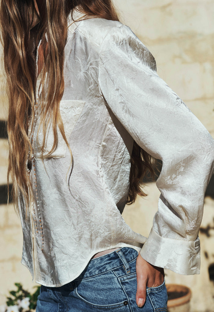 Side view of Dubois Shirt in Pearl showing flared shirt cuff, curved hem, and jacquard Naia acetate fabric