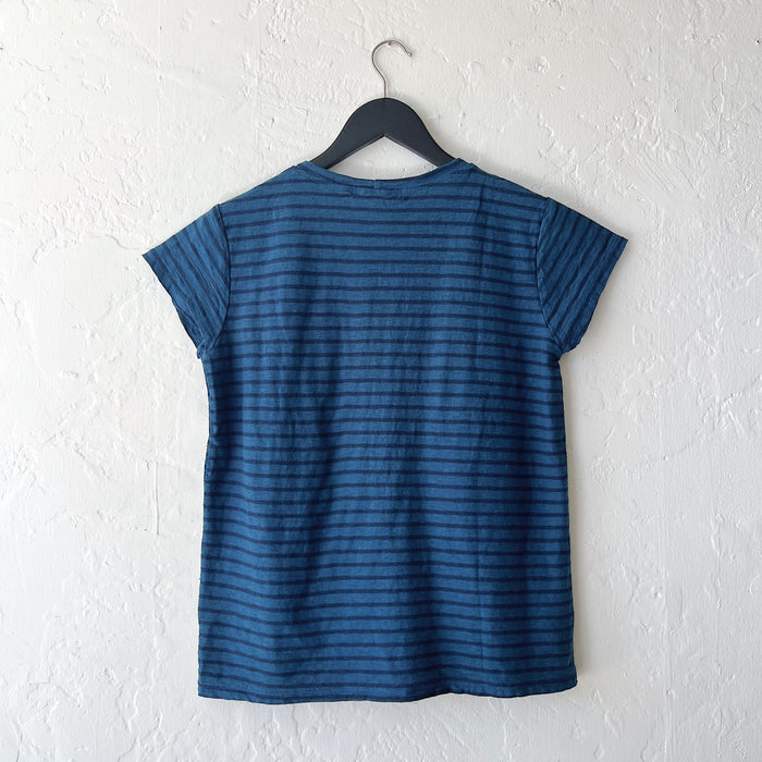 Blue striped t-shirt on a hanger against a white wall, viewed from the back