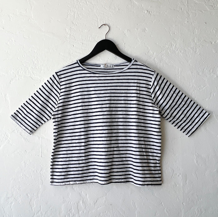 Navy and white striped shirt on a hanger against a white wall