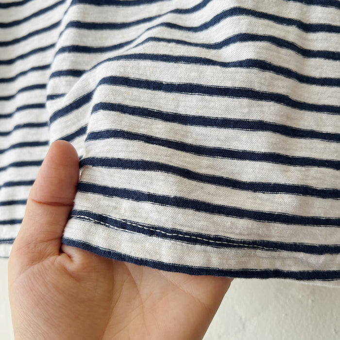 Close-up of a hand holding a piece of navy and white striped fabric.