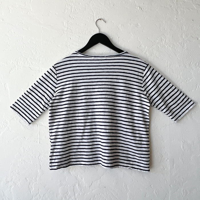 Navy and white striped shirt on a hanger against a white wall, viewed from the back