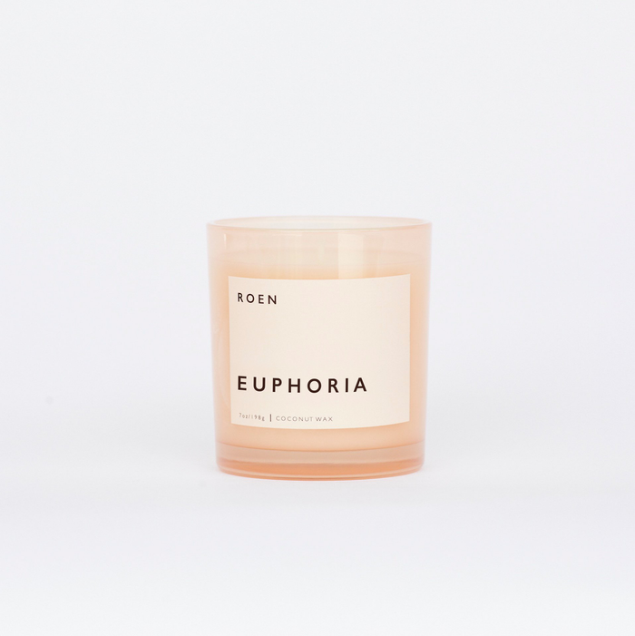 A white candle with a label that reads 'ROEN EUPHORIA', with a pale peach tint.