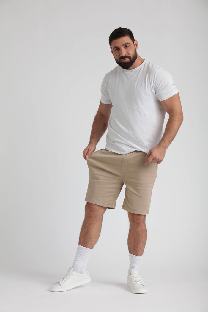Man wearing light khaki athletic shorts with white t-shirt, white socks, and white sneakers.