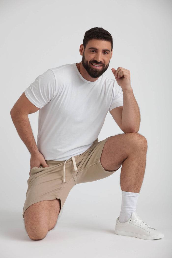 Man wearing light khaki athletic shorts with drawstring waist and white t-shirt.