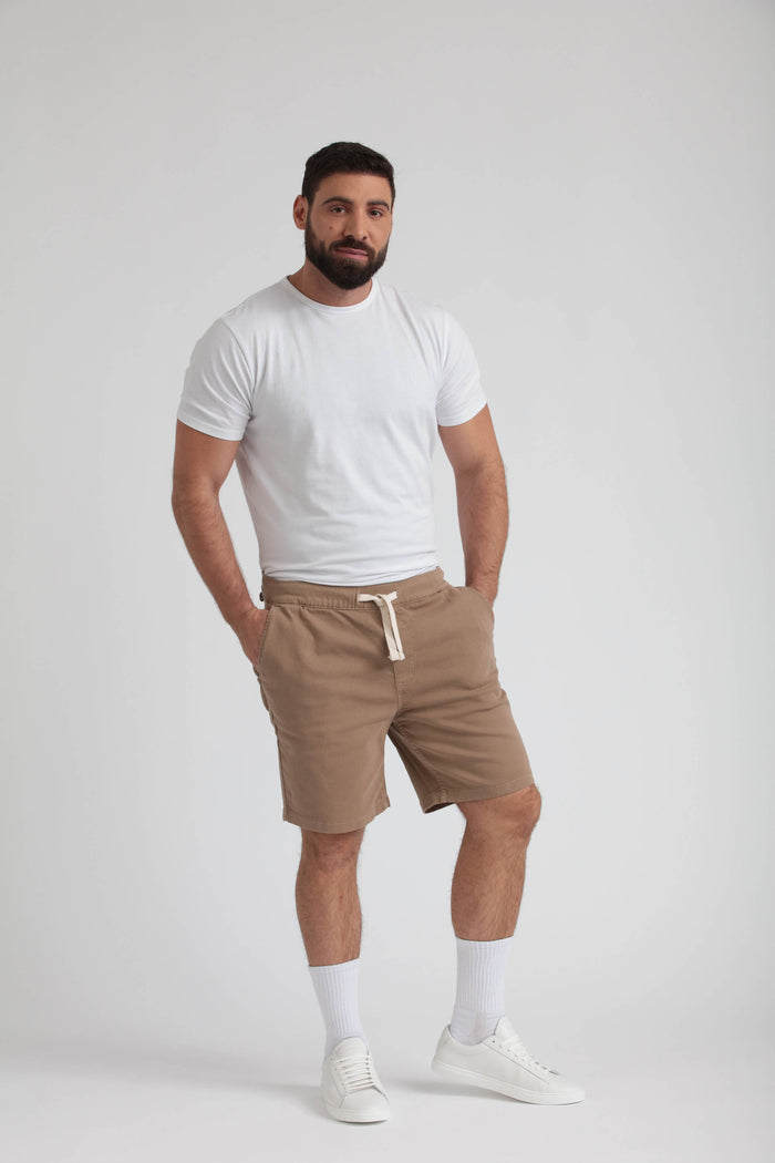 Man wearing dark khaki athletic fit shorts with drawstring waistband and white crew neck t-shirt.