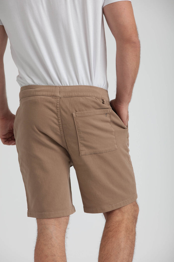 Man wearing white t-shirt and dark khaki athletic fit shorts with back pocket and side pocket visible.