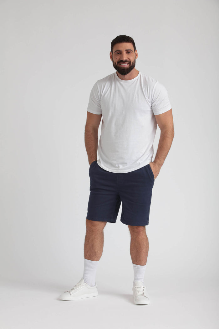 Man wearing white t-shirt and navy athletic shorts with white socks and sneakers.