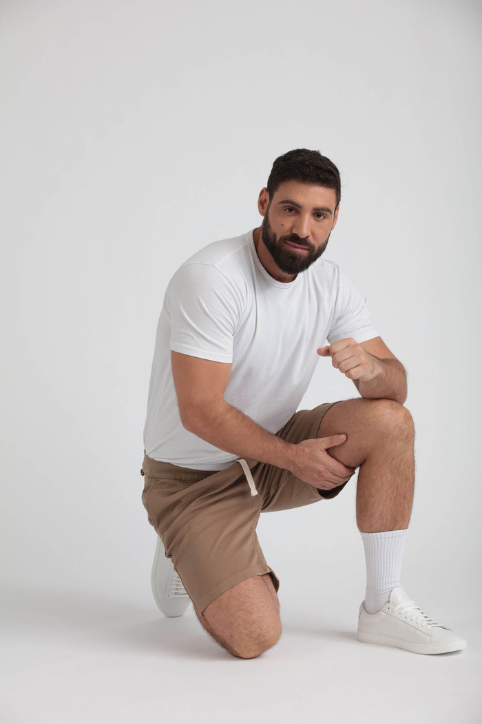 Man wearing white t-shirt and dark khaki athletic shorts with drawstring waistband.
