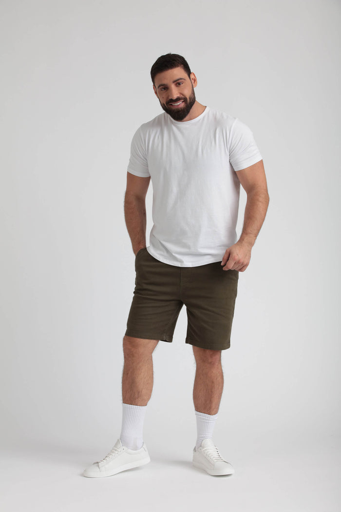 Man wearing white t-shirt and olive-green athletic shorts with white socks and sneakers.
