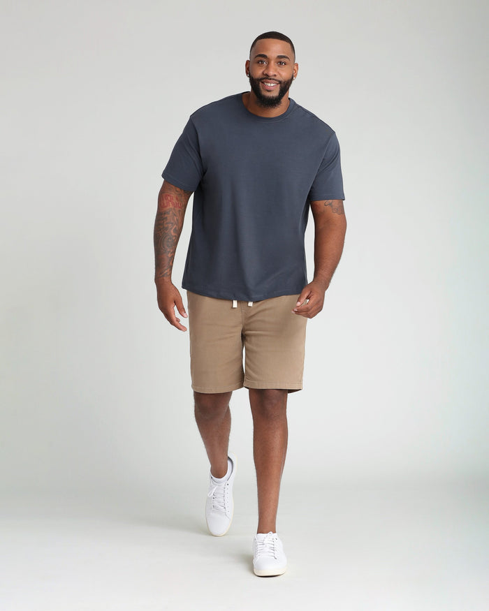 Man wearing dark khaki athletic fit shorts with drawstring waist and a navy t-shirt.