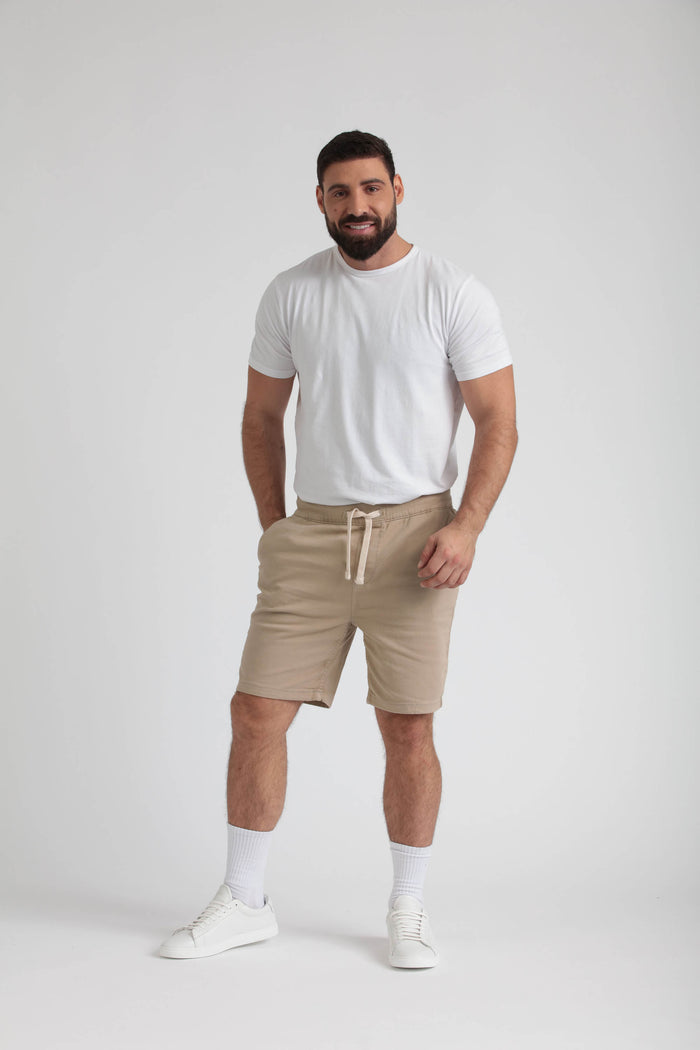 Man wearing light khaki athletic fit shorts with drawstring waist and white t-shirt.
