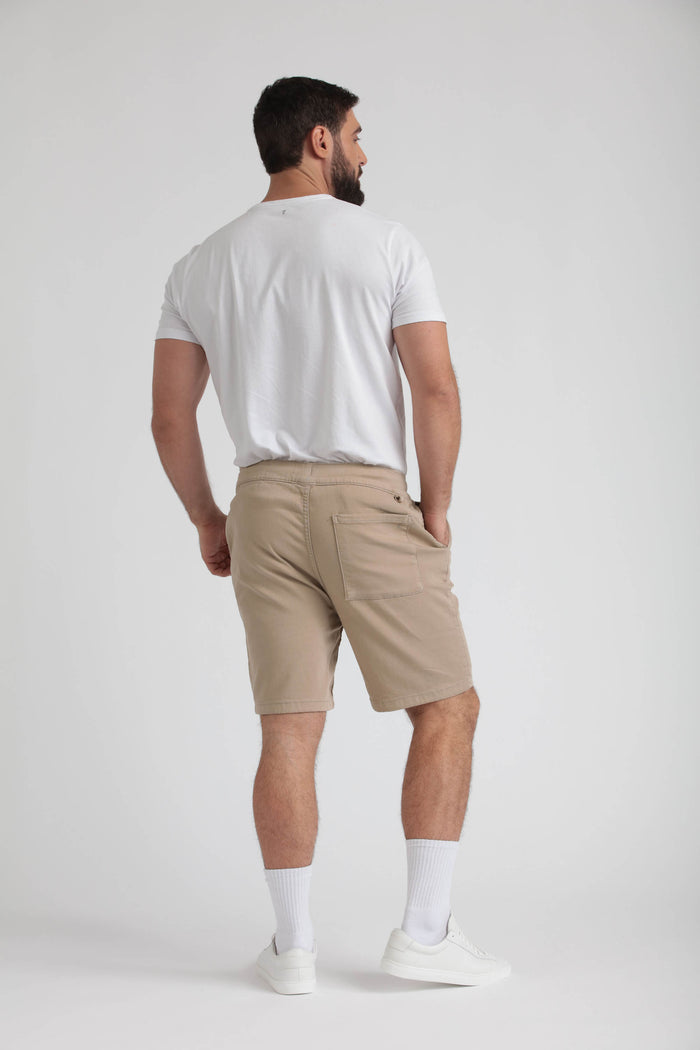 Man wearing light khaki athletic fit shorts with back pockets, white t-shirt, and white socks.