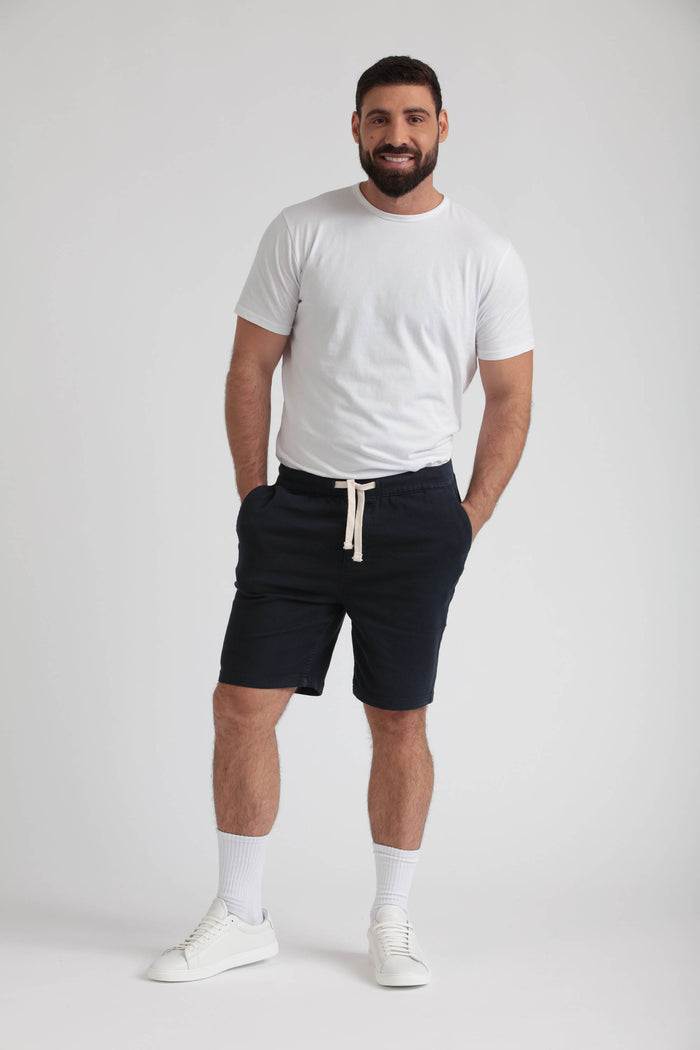 Man wearing navy athletic fit shorts with drawstring waist and white t-shirt.