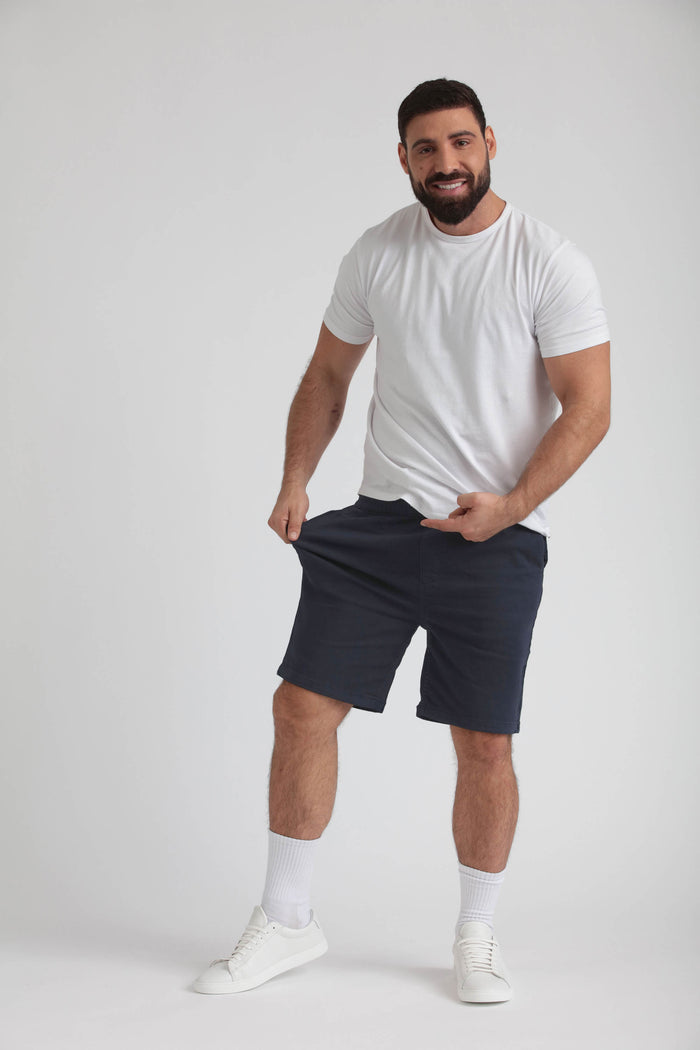 Man wearing white t-shirt and navy athletic shorts with white socks and sneakers.