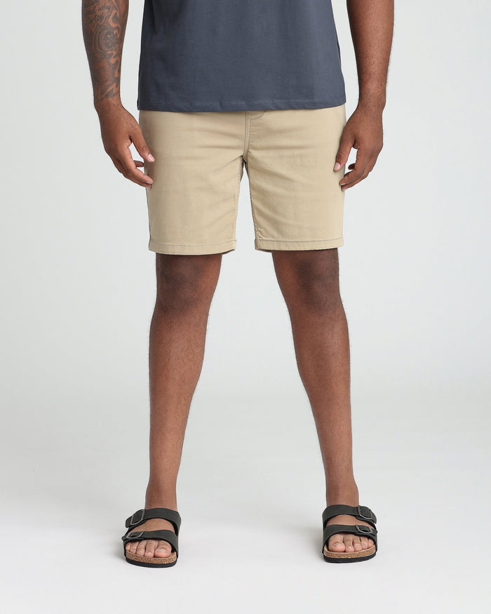 Man wearing light khaki athletic fit shorts with a dark navy shirt and black sandals.