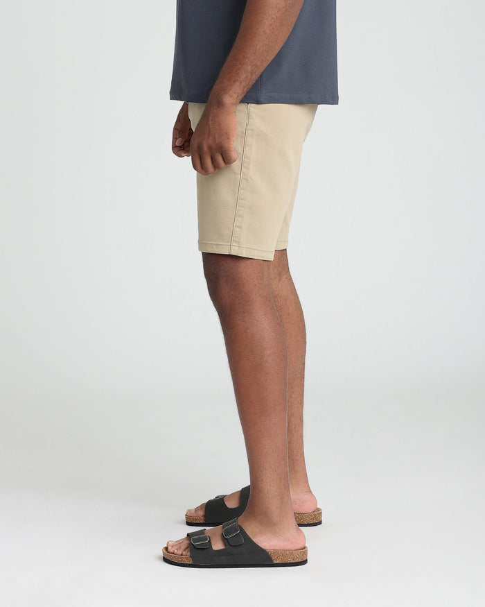 Man wearing light khaki athletic fit shorts with a dark navy shirt and black sandals.