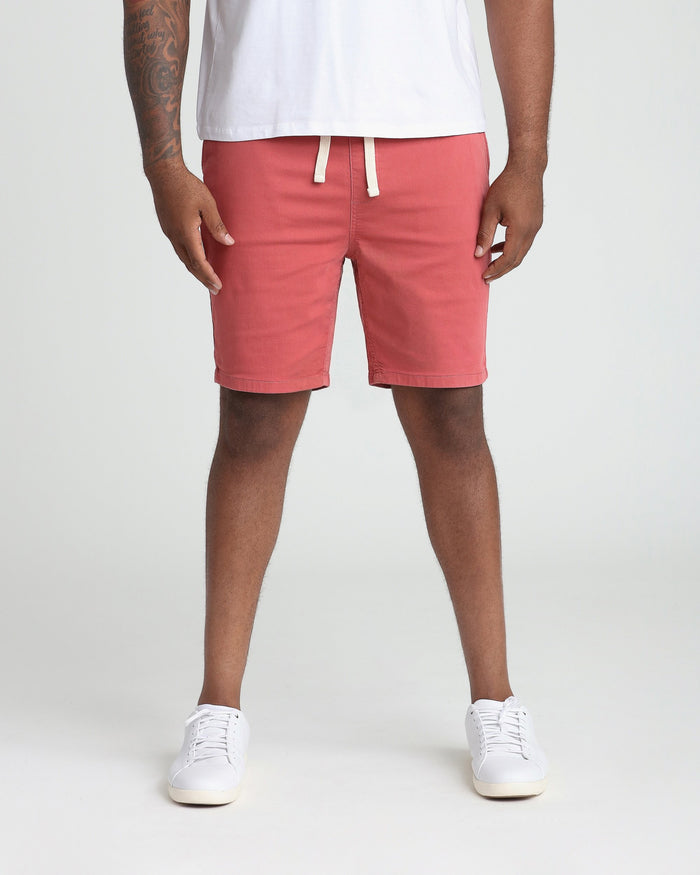 Man wearing nantucket red athletic shorts with white drawstring waistband and white sneakers.