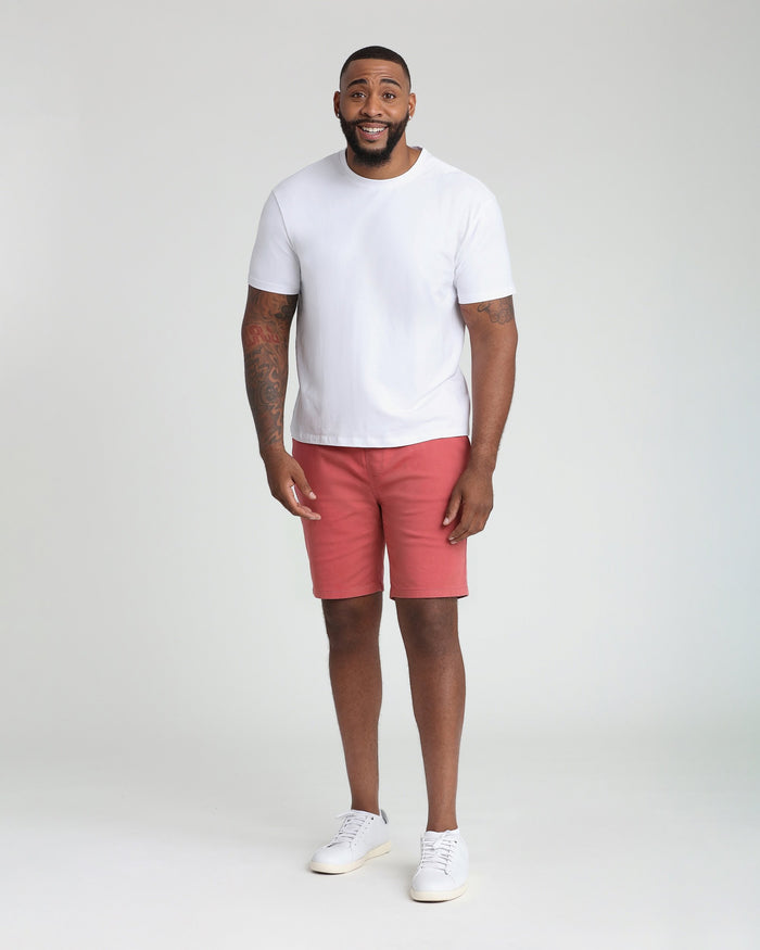 Man wearing white t-shirt and nantucket red athletic fit shorts with white sneakers.