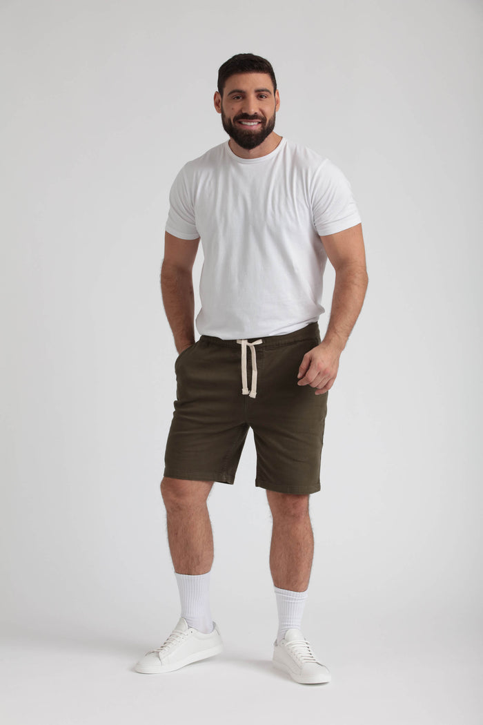 Man wearing white t-shirt and olive green athletic shorts with drawstring waistband.