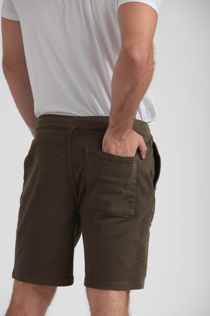 Man wearing olive green athletic shorts with front pockets, styled with white t-shirt.