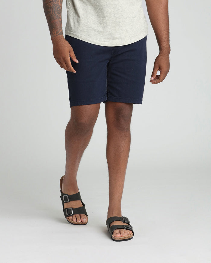 Man wearing navy athletic fit shorts with cream t-shirt and black sandals.