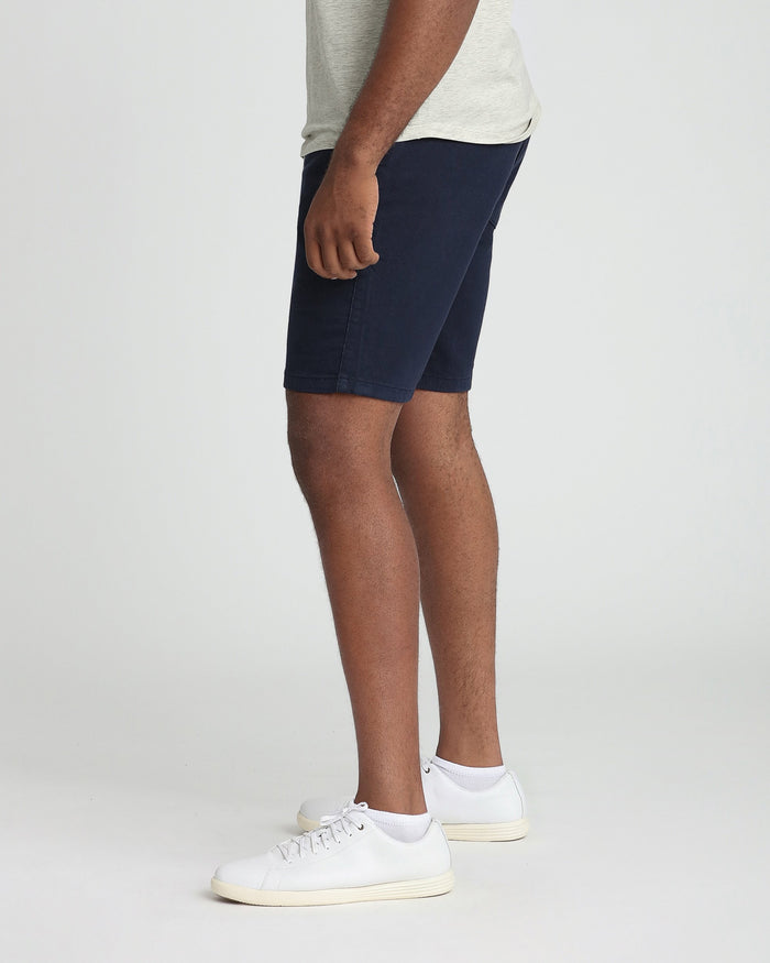 Navy athletic fit shorts on model wearing light gray shirt and white sneakers.