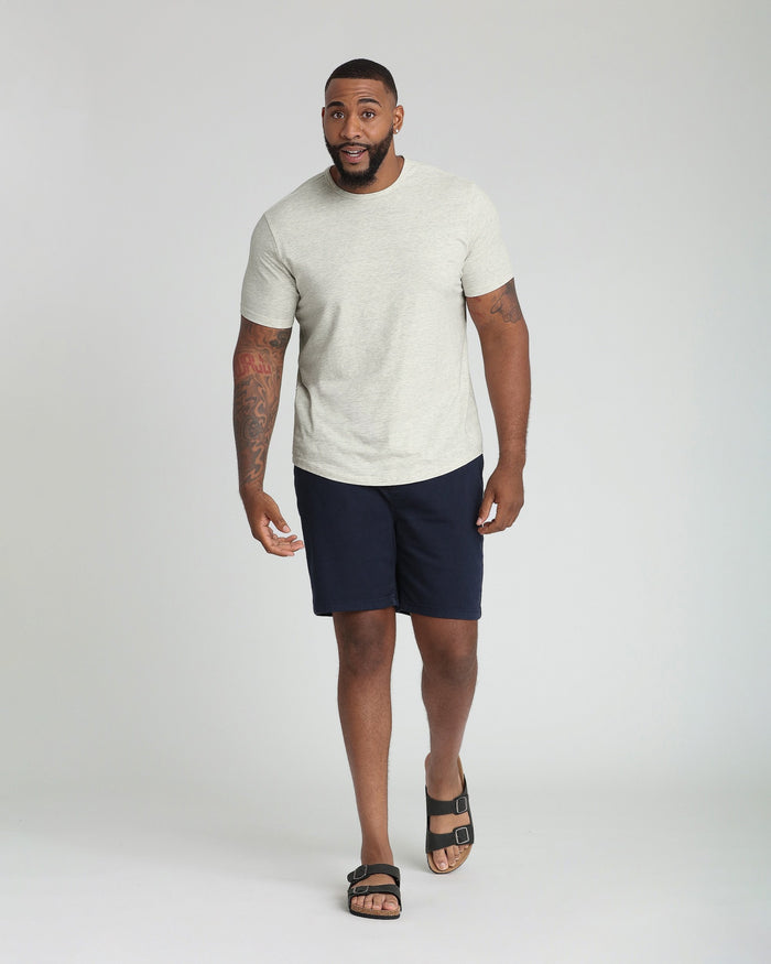 Man wearing cream t-shirt and navy athletic shorts with black sandals.