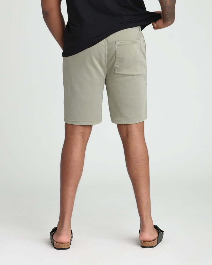 Man wearing light green athletic fit shorts with a black t-shirt, shown from behind.