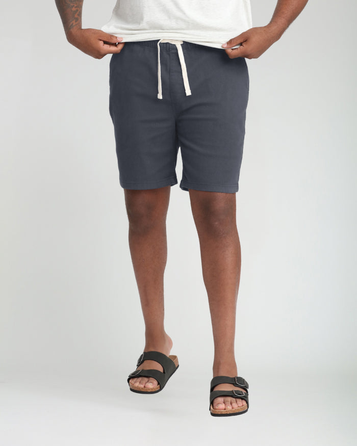 Slate gray athletic fit shorts with white drawstring waist, worn with white t-shirt and black sandals.