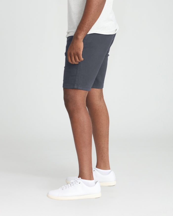 Slate gray athletic shorts on model wearing white t-shirt and white sneakers.