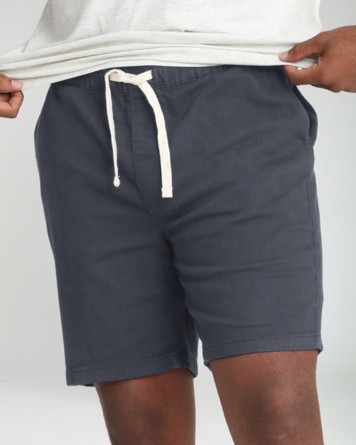 Slate gray athletic fit shorts with cream drawstring waistband, worn with white t-shirt.