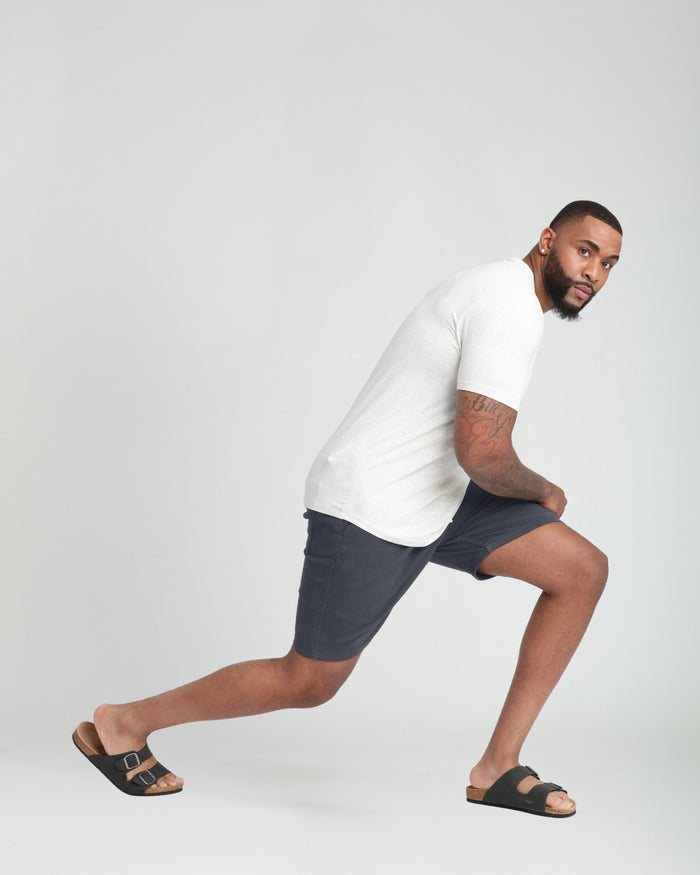 Slate gray athletic fit shorts on a man wearing a white t-shirt and black sandals.