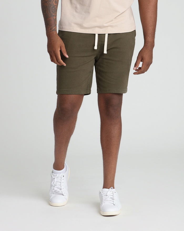 Soldier olive athletic fit shorts with white drawstring waistband, shown paired with cream t-shirt and white sneakers.