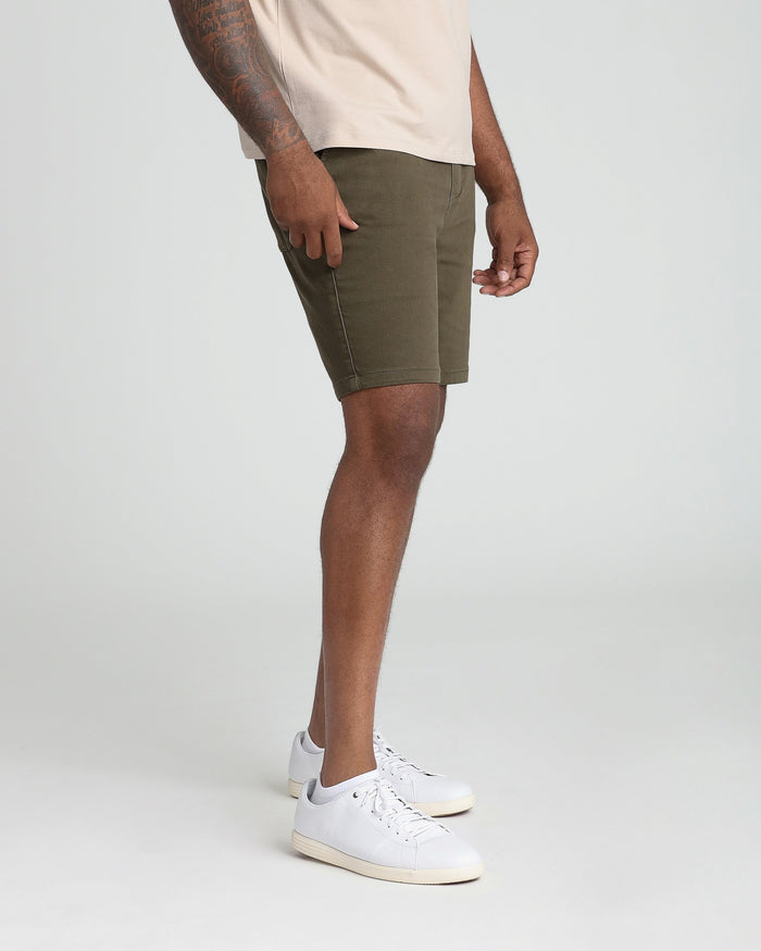Soldier olive athletic fit shorts on model with cream t-shirt and white sneakers.