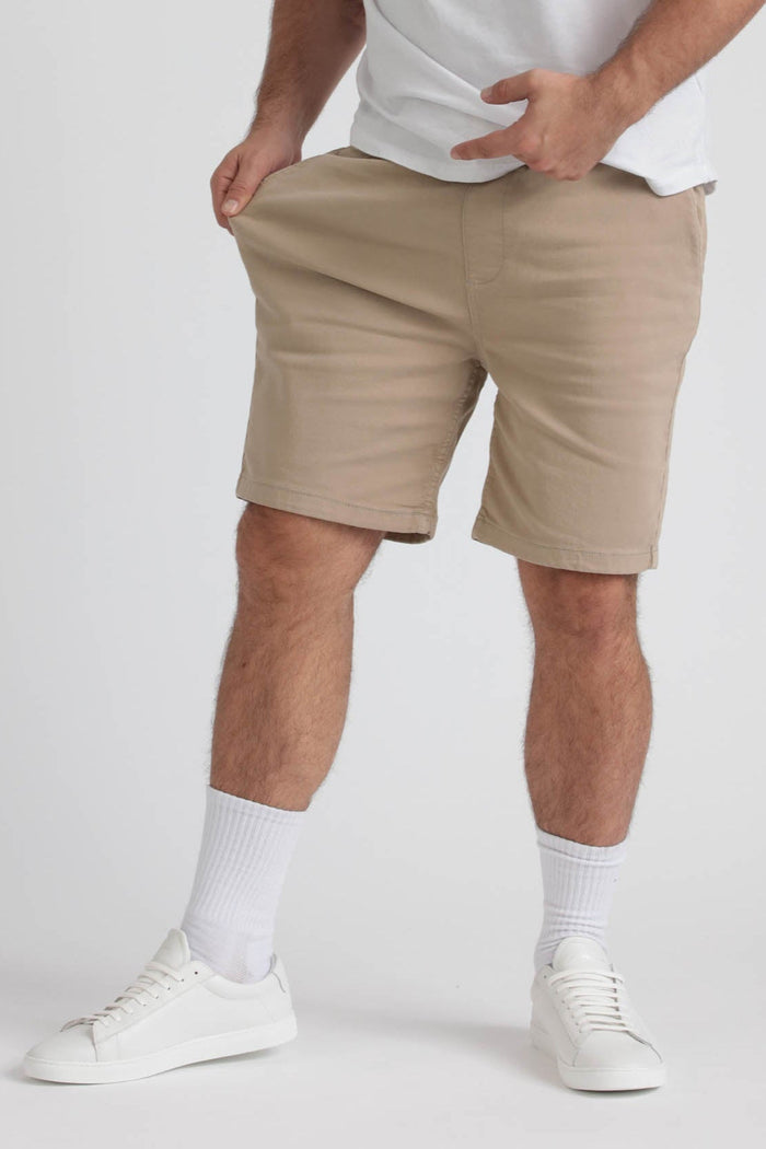 Man wearing beige athletic shorts with white t-shirt, white socks, and white sneakers.