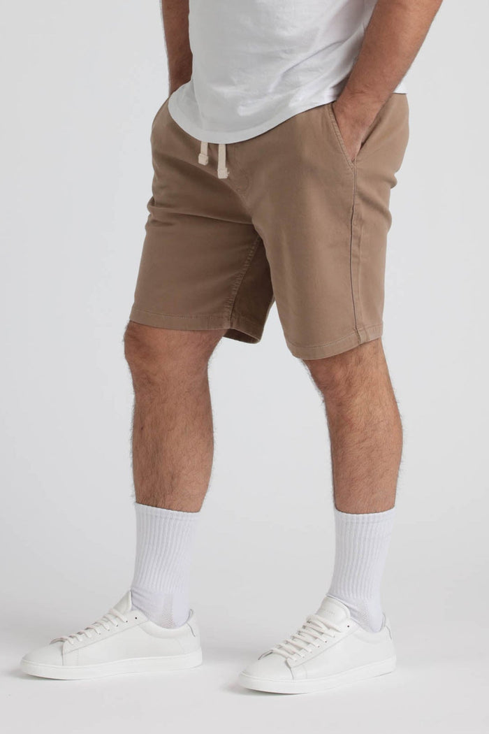 Tan athletic shorts with drawstring waistband, paired with white socks and white sneakers.