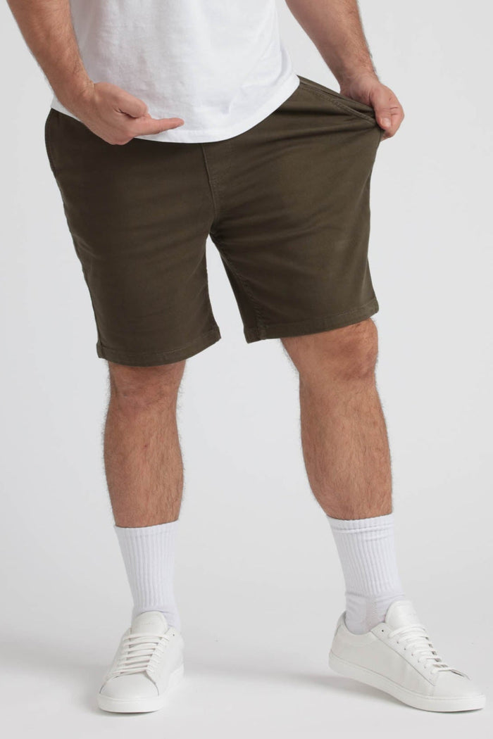 Man wearing olive green athletic shorts with white t-shirt and white sneakers.